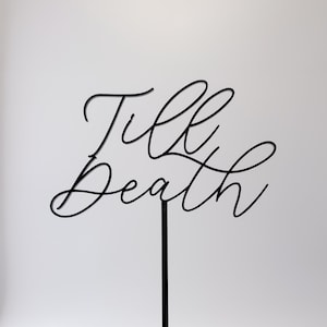 May include: Black metal cake topper with the words "Till Death" written in a cursive font.