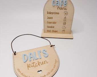 May include: Two wooden signs. One is a cafe menu with "Cafe Menu" in light blue letters, and a list of items. The other sign says "Dali's Kitchen" in light blue letters, with a heart cutout and text around the edge.