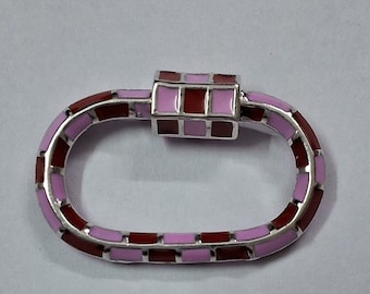 May include: Oval-shaped silver-toned clasp with a brick-like pattern in shades of pink and burgundy. The clasp has a rectangular locking mechanism in matching colors. The design is symmetrical and the clasp is set against a white background.