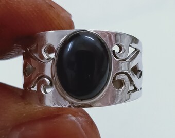 May include: A silver ring with a black oval gemstone set in a filigree design.
