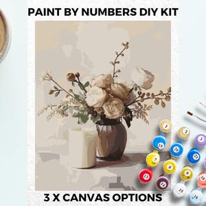 Puede incluir: Kit de pintura por números con un bodegón floral en un jarrón y una vela. El kit incluye botes de pintura y pinceles. El texto "3 X CANVAS OPTIONS" es visible.