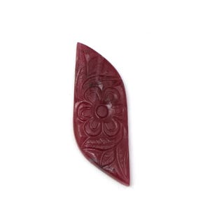 May include: A carved, maroon-colored gemstone pendant with a floral design. The pendant is shaped like a leaf, with a flower and leaf pattern carved into the surface. The gemstone is set against a white background.