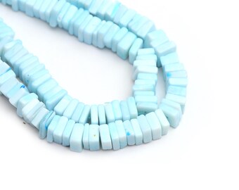 Puede incluir: Primer plano de cuentas cuadradas de color azul claro. Las cuentas son de un color azul pastel suave y están ensartadas para formar un collar o pulsera. Las cuentas son uniformes en tamaño y forma, creando un aspecto suave y consistente.