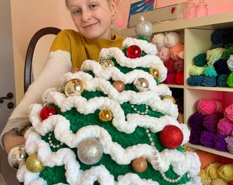 Könnte beinhalten: Ein grüner und weißer gehäkelter Weihnachtsbaum mit roten, goldenen und silbernen Ornamenten. Der Baum ist mit einer weißen Perlenkette geschmückt.