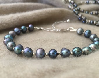 Op de afbeelding: Een delicate armband gemaakt met een rij donkerblauwe parels en zilveren kralen.