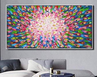 May include: Abstract painting with a colorful, swirling design. The painting features a central burst of pink and white, surrounded by a ring of blue, green, and red. The painting is framed in a black frame.