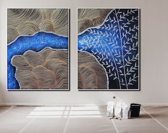 May include: Two abstract paintings with a blue, gold, and white color scheme. The left painting features a blue and gold abstract design. The right painting features a blue background with white branches.
