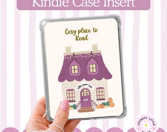 May include: A clear Kindle case insert featuring a cream-colored background with a purple-roofed house illustration. The text reads Cosy place to Read and little plum cafe. The house has yellow windows, a purple door, and orange pumpkins at the base.