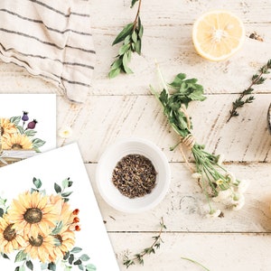 May include: Two watercolor illustrations of sunflowers in a basket and a bouquet. The illustrations are on white paper with a rustic wooden background.