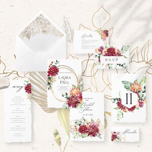 Pu&ograve; includere: Suite di inviti di nozze a tema floreale. L'invito presenta un cerchio dorato con i nomi Laura e Paul, circondato da fiori bordeaux e pesca. La carta RSVP presenta un fiore bordeaux con la parola RSVP. La carta del numero del tavolo presenta un fiore bordeaux con il numero 11.