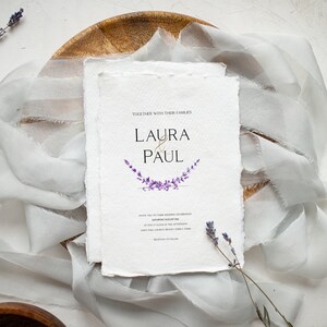 May include: Wedding invitation with a white background and a purple lavender floral design. The invitation reads "Together with their families, Laura & Paul".