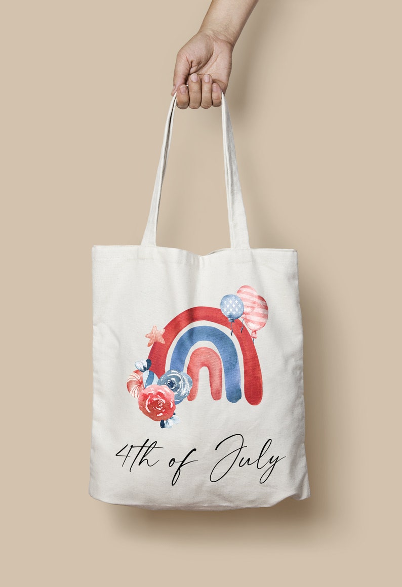 May include: A white tote bag with a red, white, and blue watercolor rainbow design. The rainbow is decorated with stars, flowers, and balloons. The text "4th of July" is printed below the rainbow.