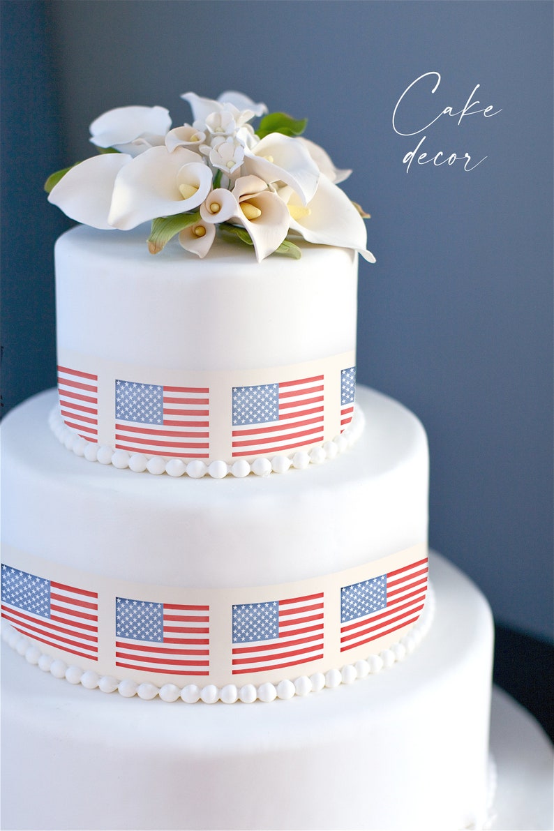 May include: A white wedding cake decorated with American flags. The cake is topped with white calla lilies.