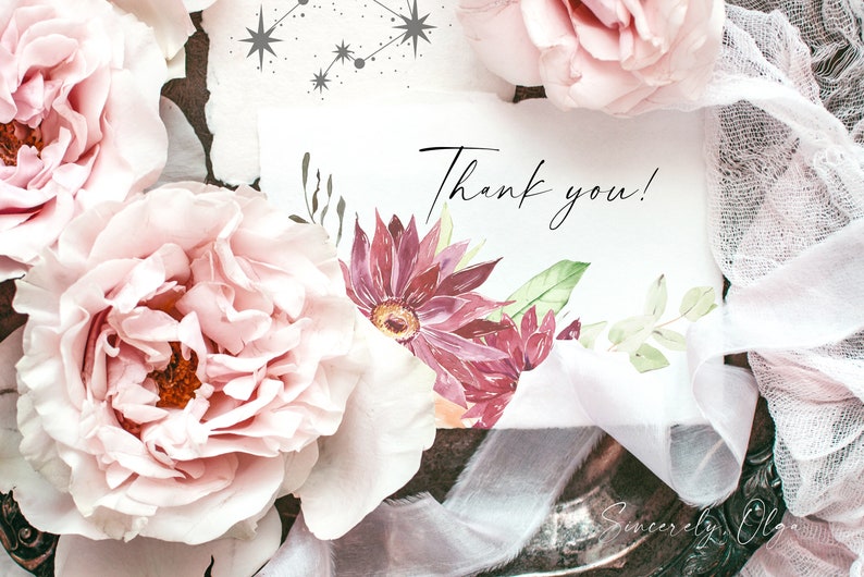May include: A white card with the text "Thank you!" written in black cursive. The card is decorated with watercolor flowers in shades of pink and green. The card is surrounded by pink roses and white lace.