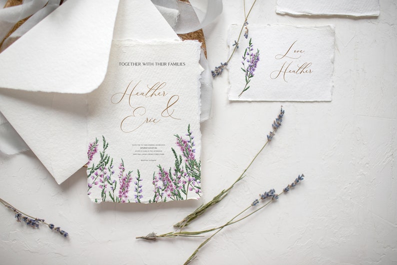 May include: Elegant wedding stationery set featuring a main invitation with the names "Heather & Eric" in gold script, surrounded by watercolor lavender. Includes matching cards and envelopes, with dried lavender sprigs.