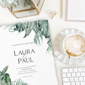 May include: Wedding invitation with tropical leaves and the text "Laura & Paul" in gold lettering. The invitation details the wedding date, time, and location: Saturday, August 2nd at five o'clock in the afternoon at Saint Paul Church, Branly Street, Paris. Reception to follow.