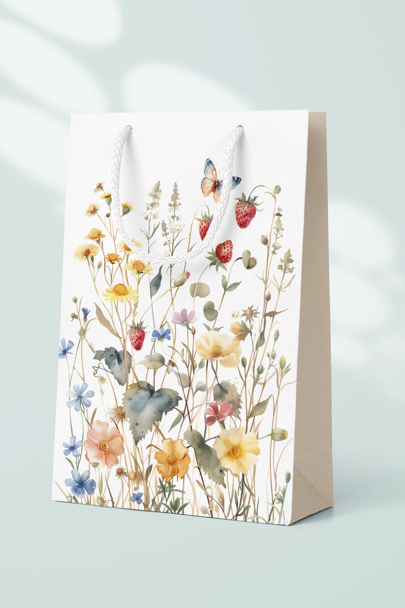 Op de afbeelding: Witte cadeauzak met een aquarelontwerp van wilde bloemen, vlinders en aardbeien. De tas heeft witte touwhandvatten.