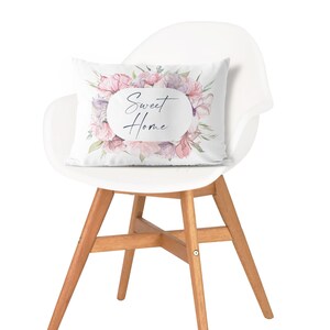 May include: A white chair with wooden legs and a floral pillow with the text "Sweet Home" in a circle.