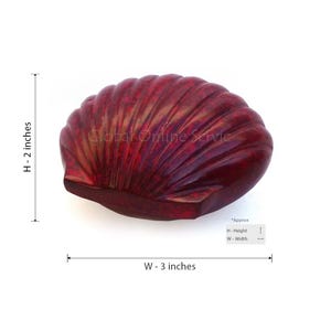 Op de afbeelding: Een donkerrood, schelpvormig decoratief object. De schelp is ongeveer 7,6 cm breed en 5,1 cm hoog. De tekst "Global Online Service" is zichtbaar op de schelp.