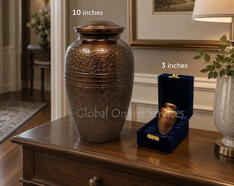 Op de afbeelding: Een grote, donkerbronskleurige metalen urn met een ingewikkelde bloemengravure, gelabeld 10 inches, naast een kleinere bijpassende aandenken-urn in een met blauw fluweel beklede doos, gelabeld 3 inches, met tekst voor groottevergelijking.