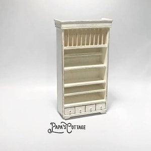 May include: White wooden hutch with a plate rack, four drawers, and five shelves. The hutch is a miniature piece of furniture.