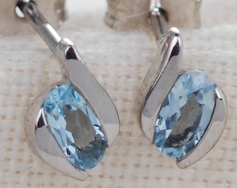 May include: A pair of silver stud earrings with a light blue oval gemstone set in each earring.