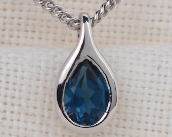 May include: A silver chain necklace with a teardrop pendant featuring a blue gemstone.