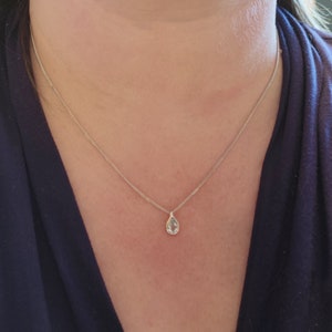 May include: A silver chain necklace with a teardrop-shaped pendant featuring a clear gemstone.