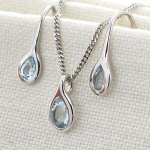 May include: A silver necklace and earrings set with teardrop-shaped blue gemstones.