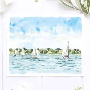 May include: Watercolor painting of sailboats on a lake under a blue sky with clouds. The artwork features several white sailboats with their sails up, sailing on blue water. Green trees line the distant shore. The painting is on white paper.