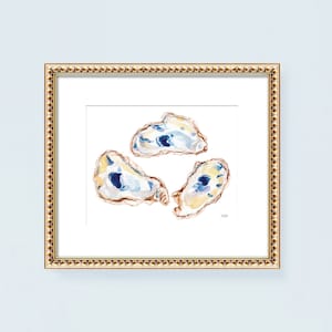 May include: A framed watercolor print featuring three oyster shells. The shells are painted with shades of blue, yellow, and brown, set against a white background. The frame is gold with a detailed border, adding a touch of elegance.