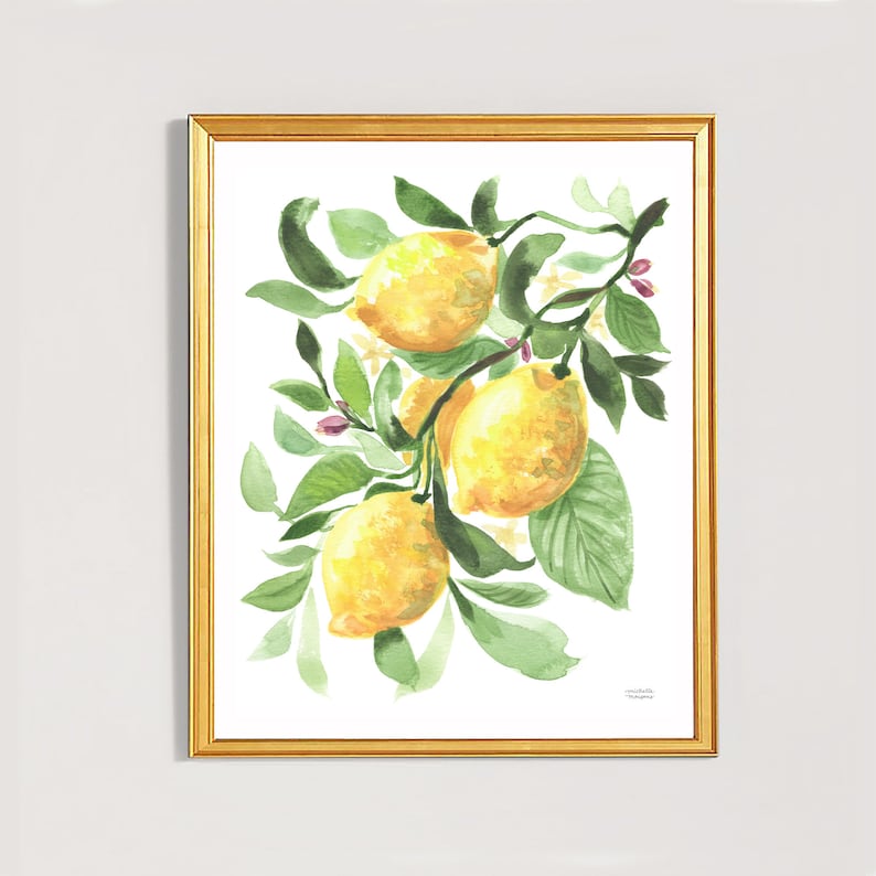 May include: A framed watercolor print featuring a branch of lemons. The lemons are yellow with green leaves and small pink flowers. The artwork is in a gold frame, creating a bright and cheerful aesthetic. The painting is on a white background.