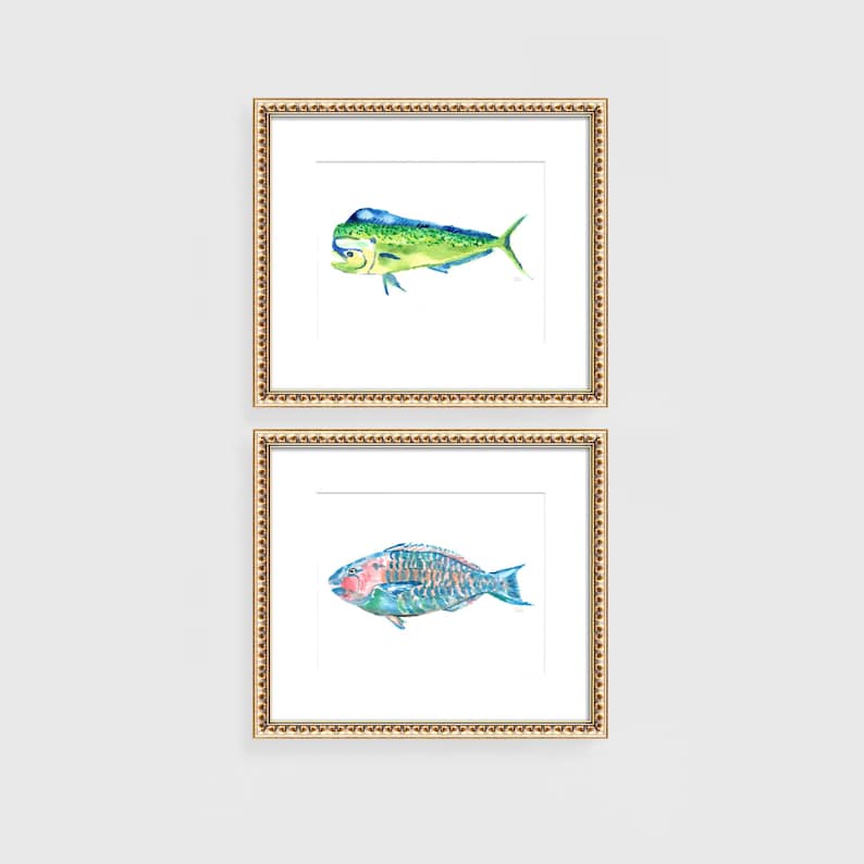 May include: Two framed watercolor prints of fish. The top print features a green and yellow mahi-mahi. The bottom print shows a colorful parrotfish. Both prints are in gold ornate frames, perfect for coastal decor.