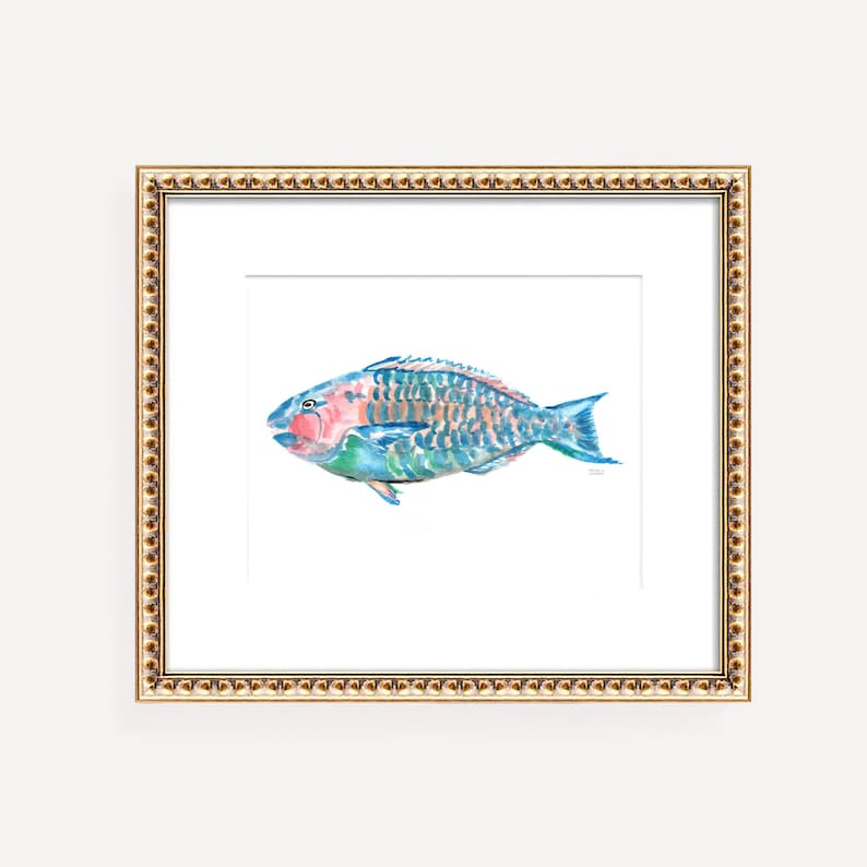 May include: A framed watercolor print of a colorful fish. The fish features shades of blue, green, pink, and orange. The artwork is set against a white background and framed in a gold-colored frame. The frame has a detailed, textured border.