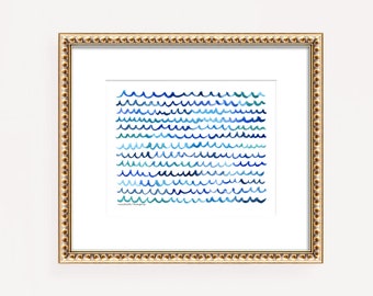 May include: A framed print of a watercolor painting of blue waves on a white background. The waves are hand-drawn and have a whimsical feel. The print is framed in a gold frame with a beaded edge.