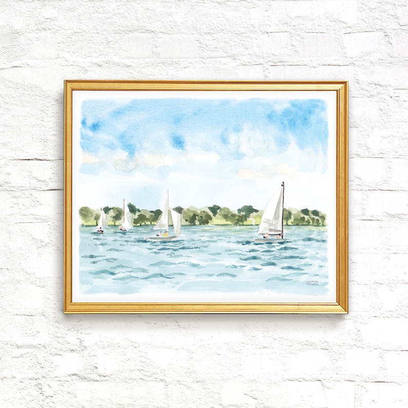 May include: Watercolor painting of sailboats on a lake under a blue sky. The artwork features several white sailboats with their sails up, sailing on a light blue body of water. Green trees line the horizon, and the painting is framed in a gold frame.