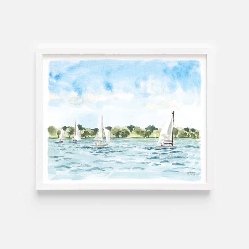 May include: Watercolor painting of sailboats on a lake under a blue sky with fluffy clouds. The artwork features several white sailboats with their sails up, sailing on the blue water. Green trees line the distant shore, and the painting is framed in a white border.