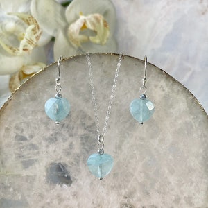 May include: A silver necklace and earrings set with light blue heart-shaped aquamarine stones.