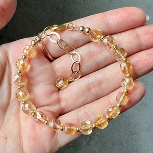 May include: A gold bracelet with a chain clasp and faceted citrine beads.