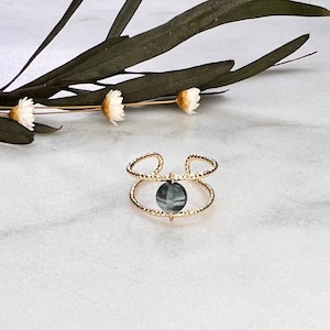 Puede incluir: Anillo de oro con una banda texturizada y una piedra preciosa gris en el centro.