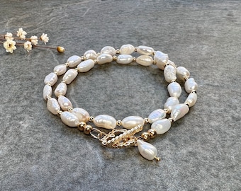 May include: A white pearl necklace with a gold clasp and a single pearl pendant. The necklace is made of large, irregular-shaped pearls.