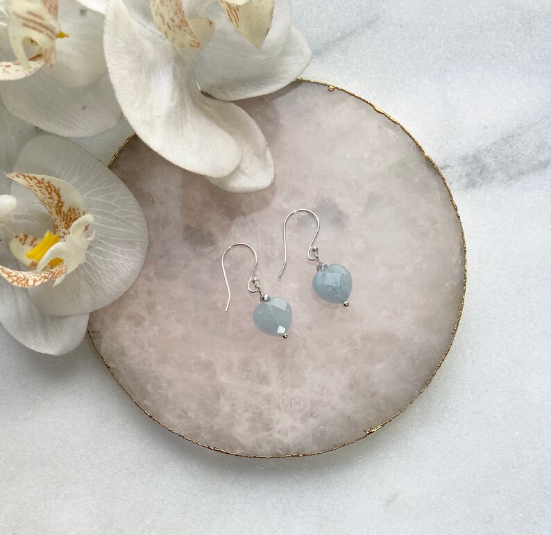 May include: A pair of silver earrings with light blue heart-shaped gemstone drops.