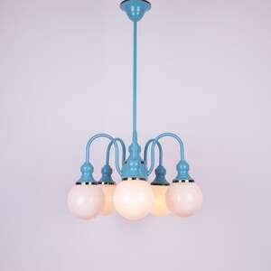 May include: A blue and gold chandelier with five white globe-shaped light bulbs.