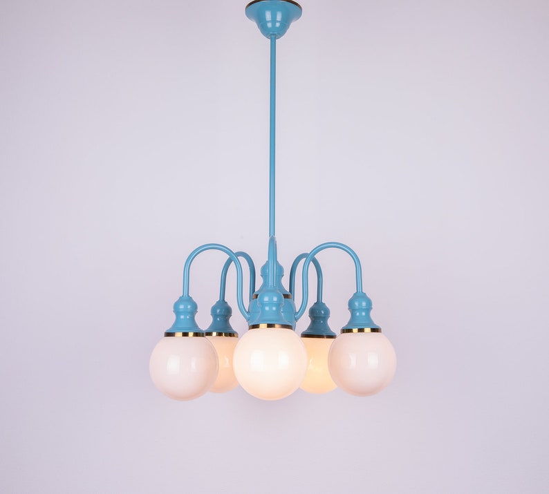 May include: A blue and gold chandelier with five white globe-shaped light bulbs.