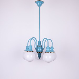 May include: A light blue chandelier with six white globe-shaped light bulbs. The chandelier has a gold trim around the base of each bulb.