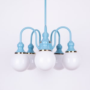 May include: A light blue chandelier with five white globe-shaped light bulbs. The chandelier has a gold trim around the base of each bulb.