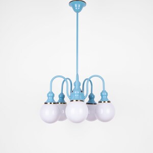 May include: A light blue chandelier with five white globe-shaped light bulbs. The chandelier has a gold trim around the base of each bulb.