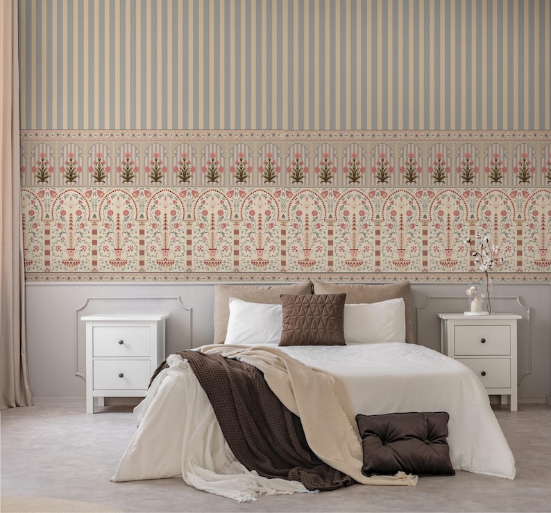 May include: Bedroom interior with a bed, nightstands, and patterned wallpaper. The wallpaper features vertical stripes and a decorative border with floral and geometric designs in muted tones of beige, pink, and brown. The bed has white linens and brown pillows.