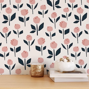 May include: A floral wallpaper pattern with pink flowers and dark blue leaves on a cream backdrop. A gold candle holder and a white bowl with gold spheres are on a wooden surface. The wallpaper is the main focus.