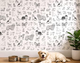 Pode incluir: Um cão de cor clara está deitado num chão de madeira ao lado de duas taças de metal em frente a uma parede coberta com papel de parede com um padrão repetitivo de desenhos de linhas a preto e branco de várias raças de cães. Uma planta verde está à direita.